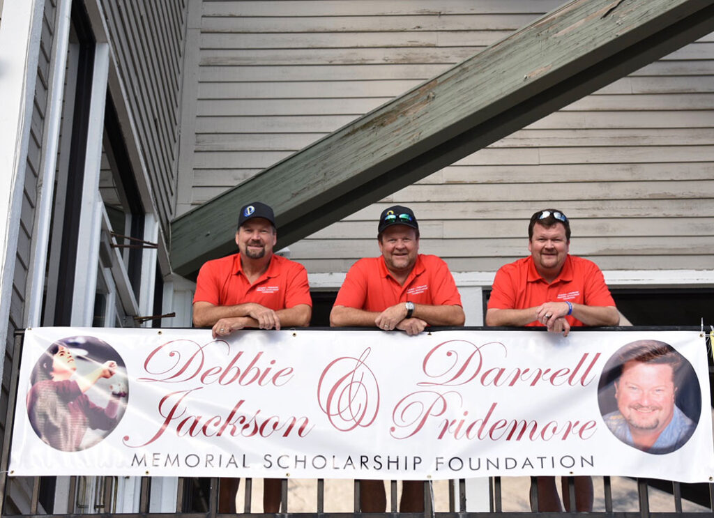 three staff members with Legacy Auto Clinic Castle Rock honor family members at fundraising event